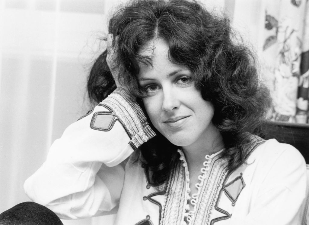 Grace Slick leans her head on her hand while sitting in a living room.