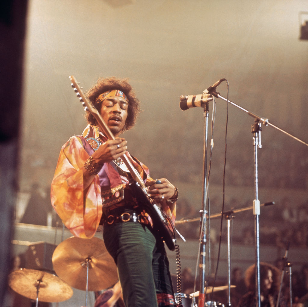 Jimi Hendrix plays guitar with his eyes closed onstage.