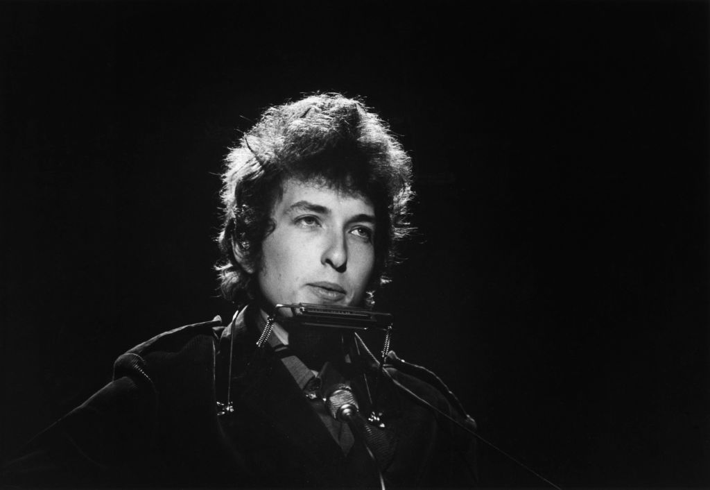 Bob Dylan plays guitar onstage.