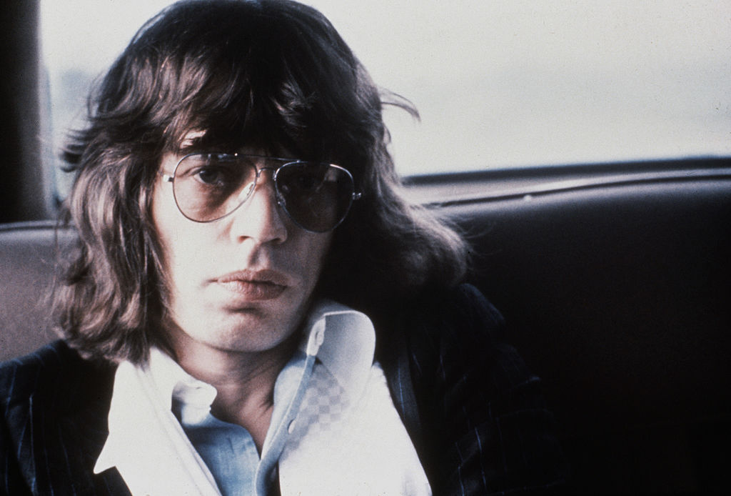 Mick Jagger lounges in the back of a car.