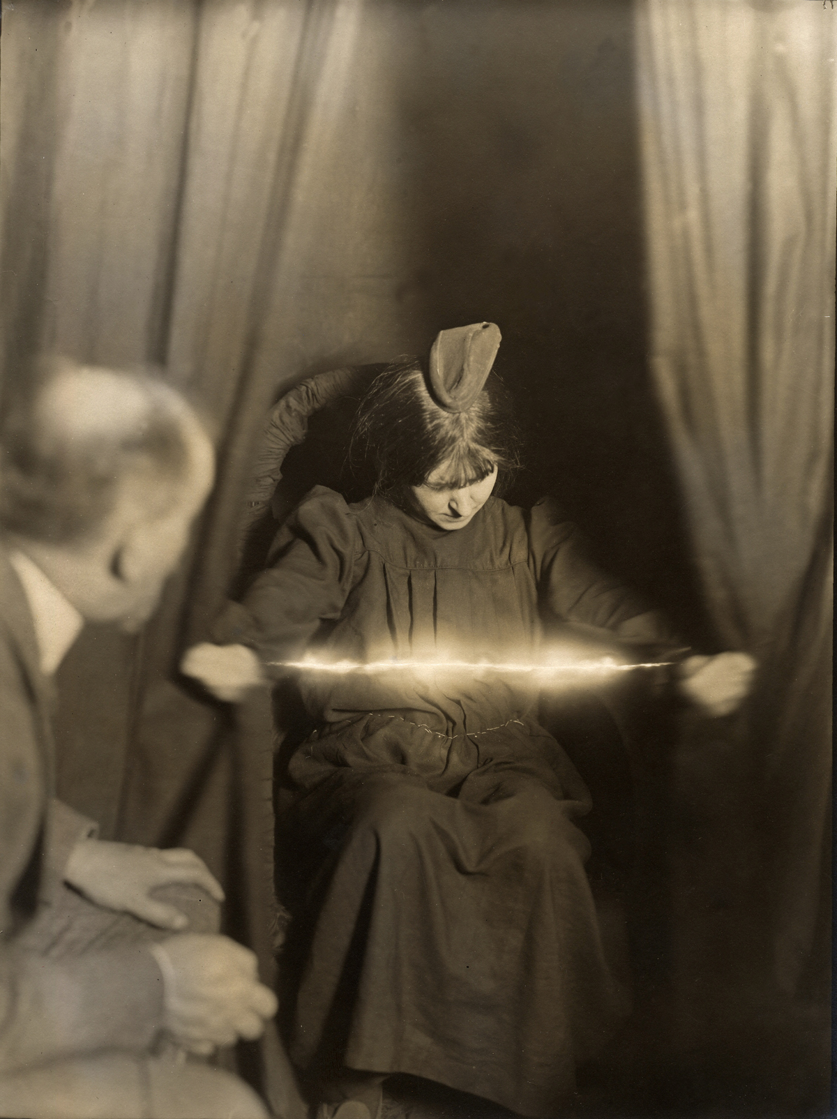 The medium Eva C. with a materialization on her head and a luminous apparition between her hands. On May 17, 1912.