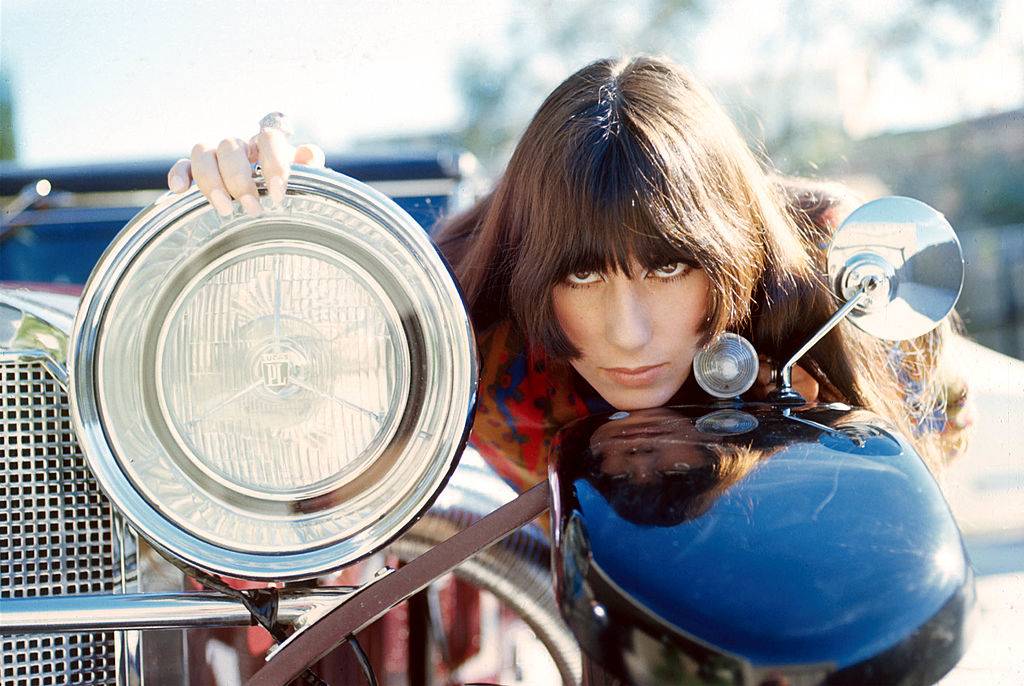 Cher models near a car headlight.