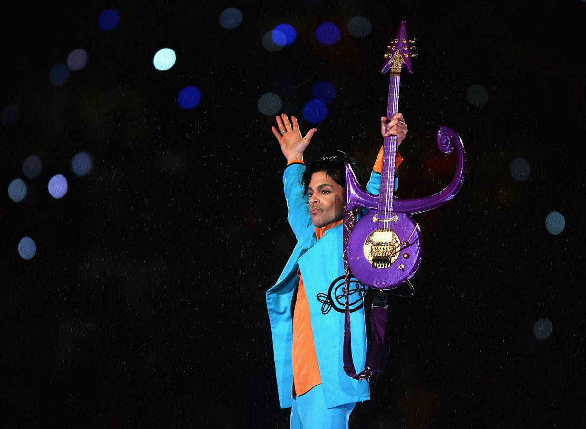 Prince holds up his symbol guitar at the super bowl half time show in 2007.
