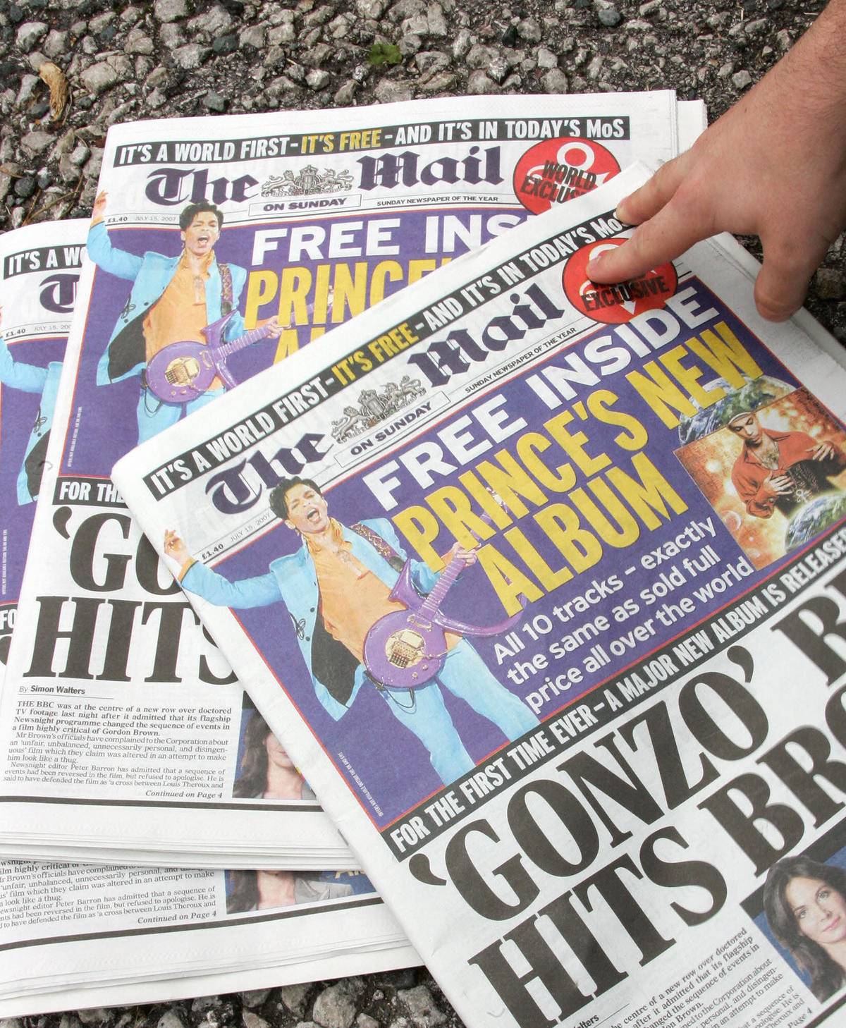 A man picks up a copy of British newspaper The Mail, which includes a copy of the new album by Prince.