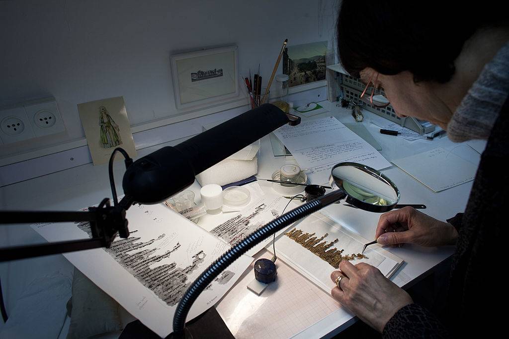 Woman inspecting pieces of parchment 