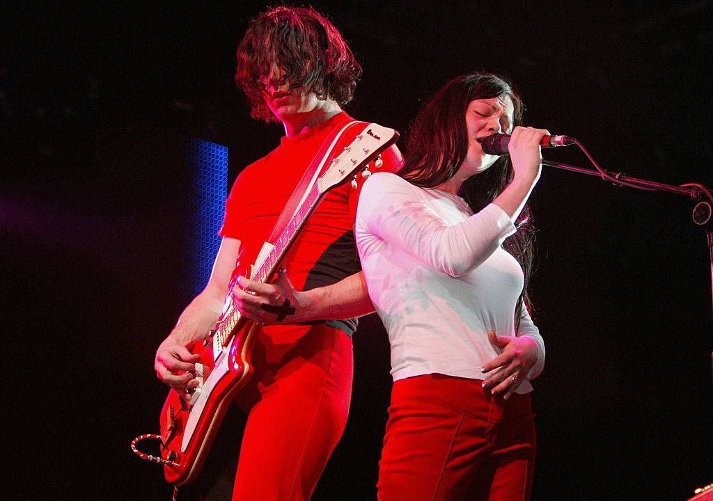 Jack plays guitar while Meg sings onstage.