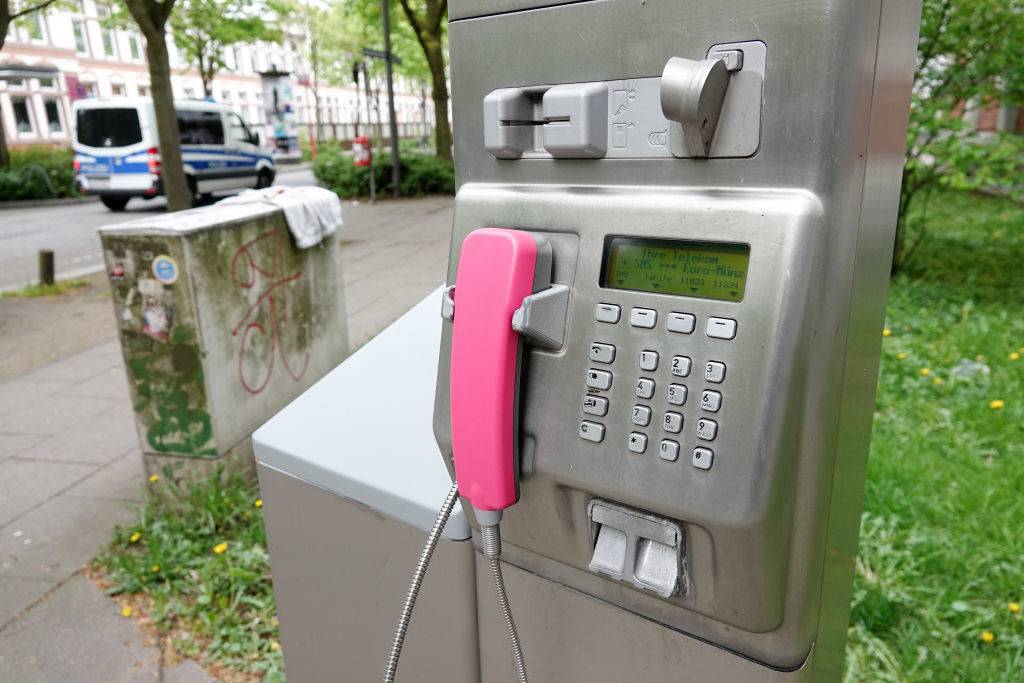 A public pay phone in the Bernhard-Nocht-Strasse in the district St. Pauli, in the background a police car is driving.
