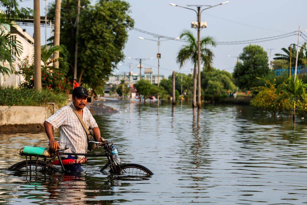People try to cross the road due to a flood in Muara Baru, on June 6, 2020 in Jakarta, Indonesia. According to the Climatology and Geophysics Meteorology Agency