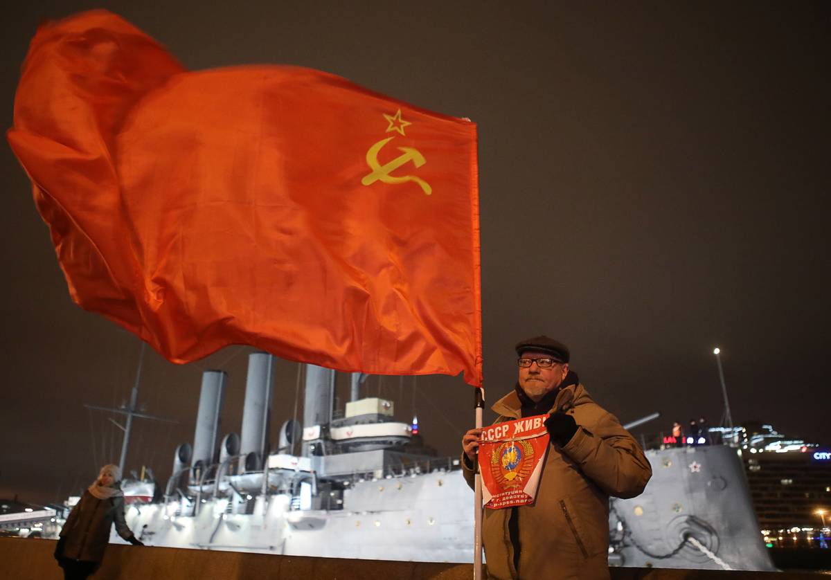 A man holds up a Soviet flag to commemorate the Bolshevik revolution.
