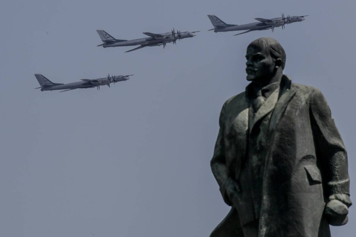 Planes fly behind a Lenin sculpture.