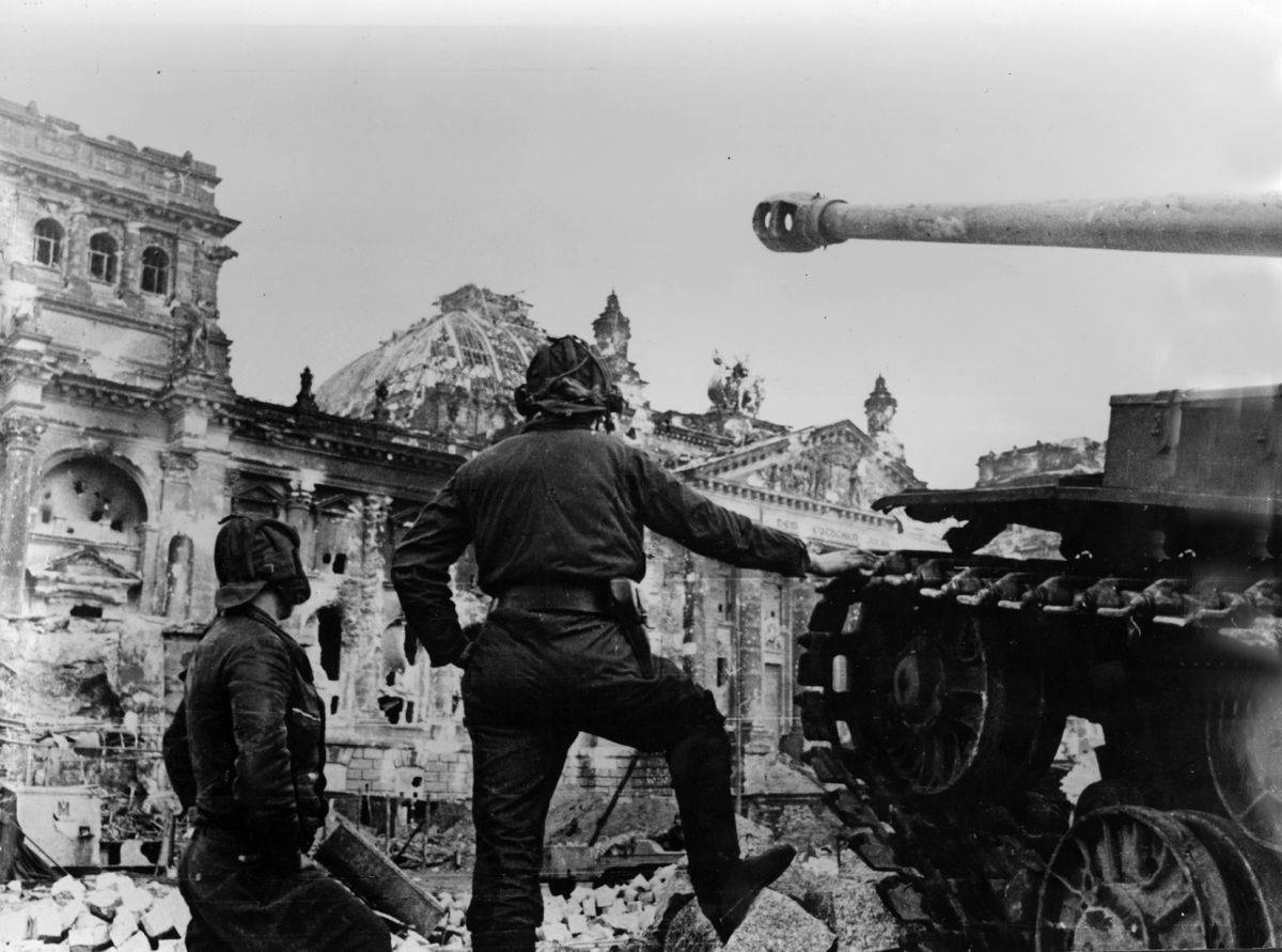 Soviet soldiers stand next to a tank in World War II.