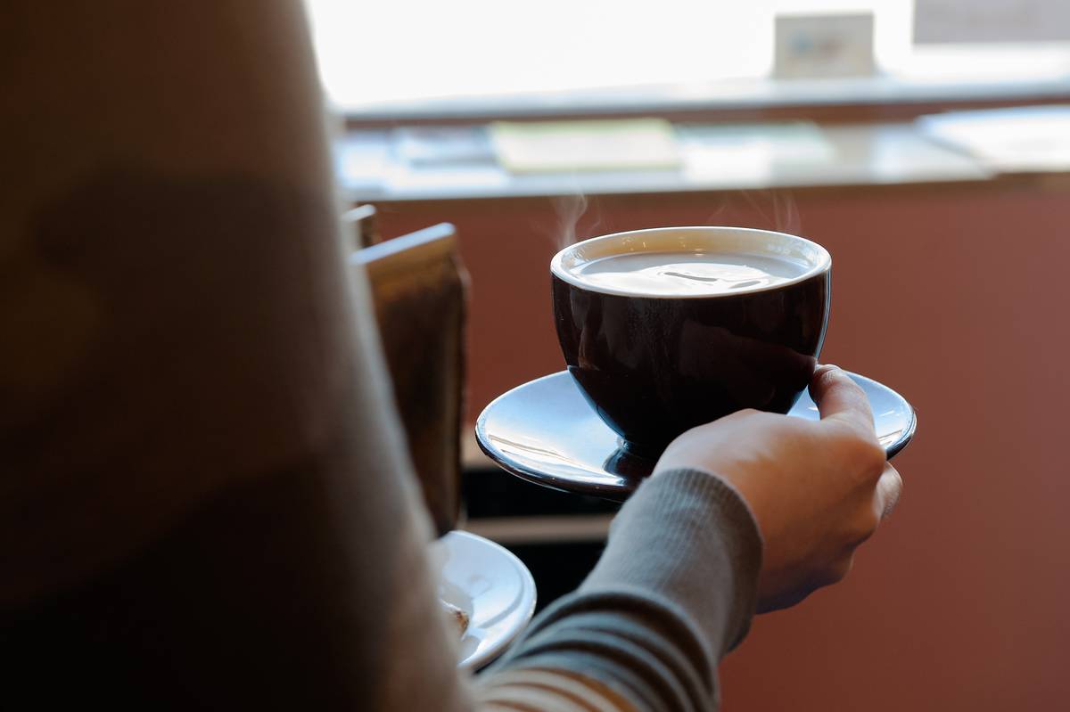 A customer carries a cup of coffee to her table