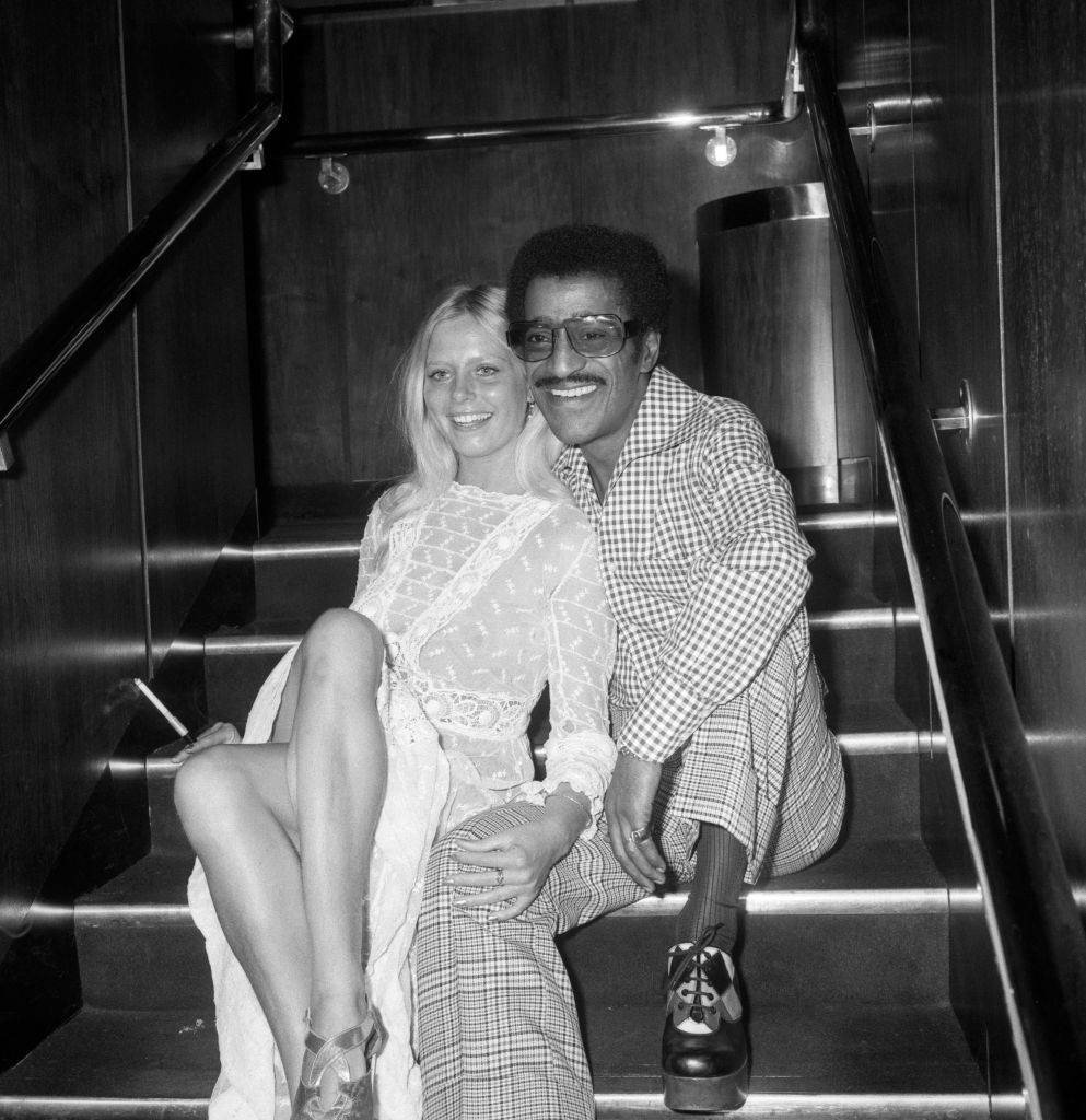 American entertainer Sammy Davis Jr, finds company at a party given for him at the Playboy Club in London. She is jewellery designer Anulka Dziubinska, 20, who has made the centrefold of Playboy magazine as Playmate of the Month.