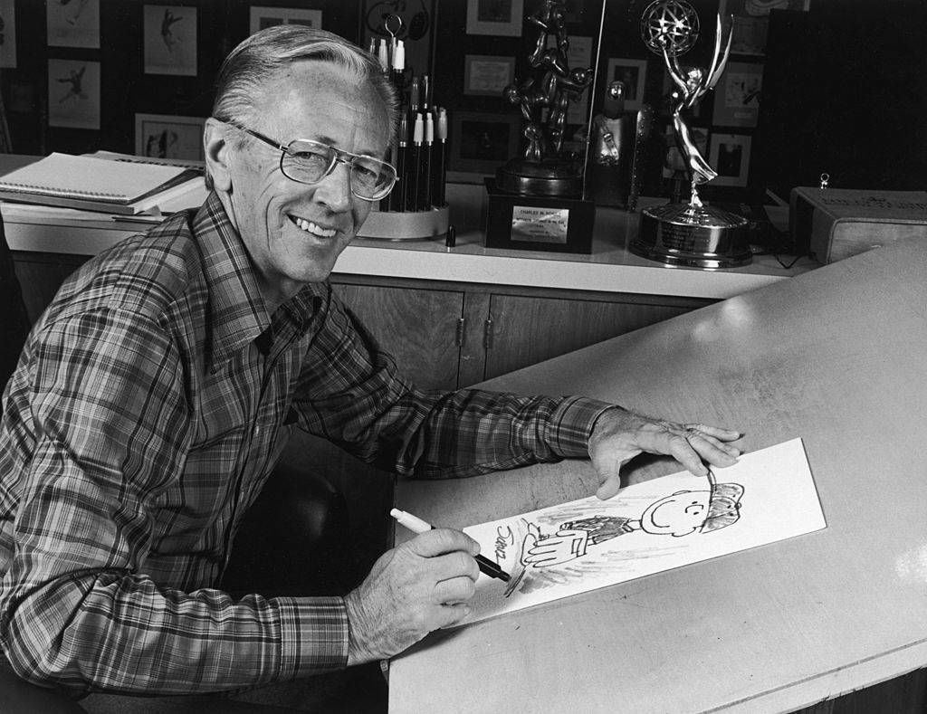 charles m schulz at his studio drawing table