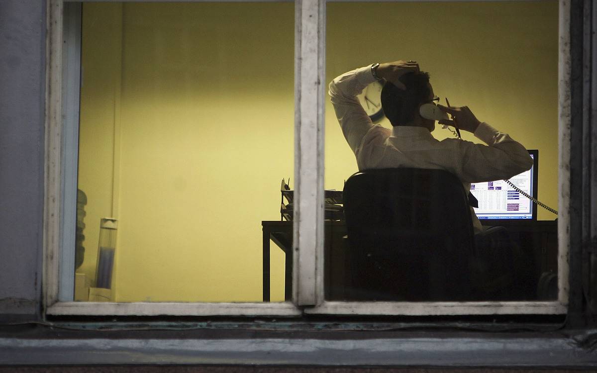 A compliance worker is seen talking on the phone through a window.