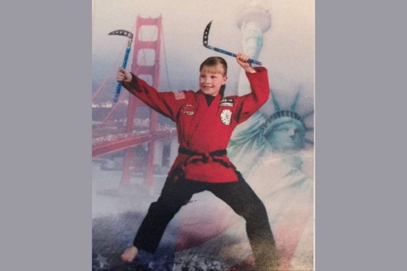 School photo of girl in karate gear holding kamas