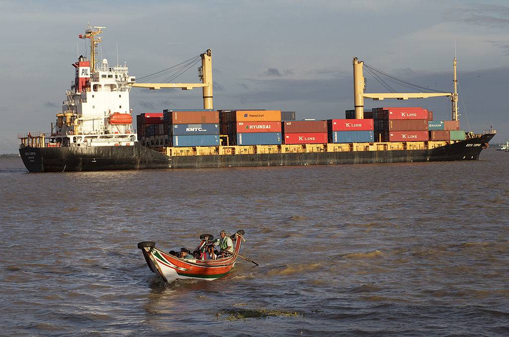 A small commuter boat makes way in front of container ship