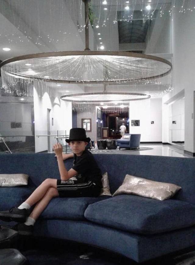 kid in fedora hat sitting in fancy lobby