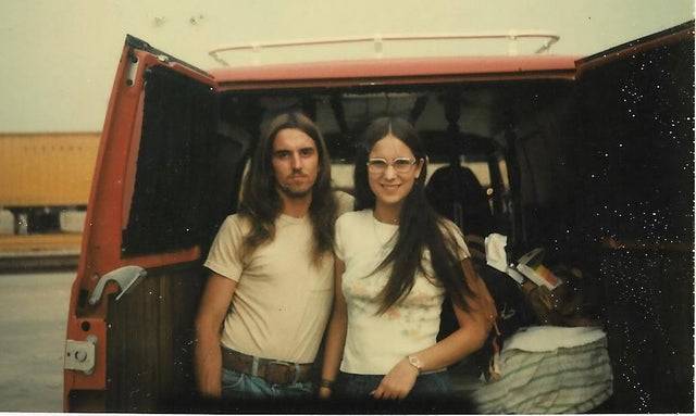 young couple in the '70s standing in front of van