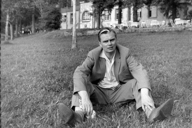 man with blonde streak in hair sitting on the grass