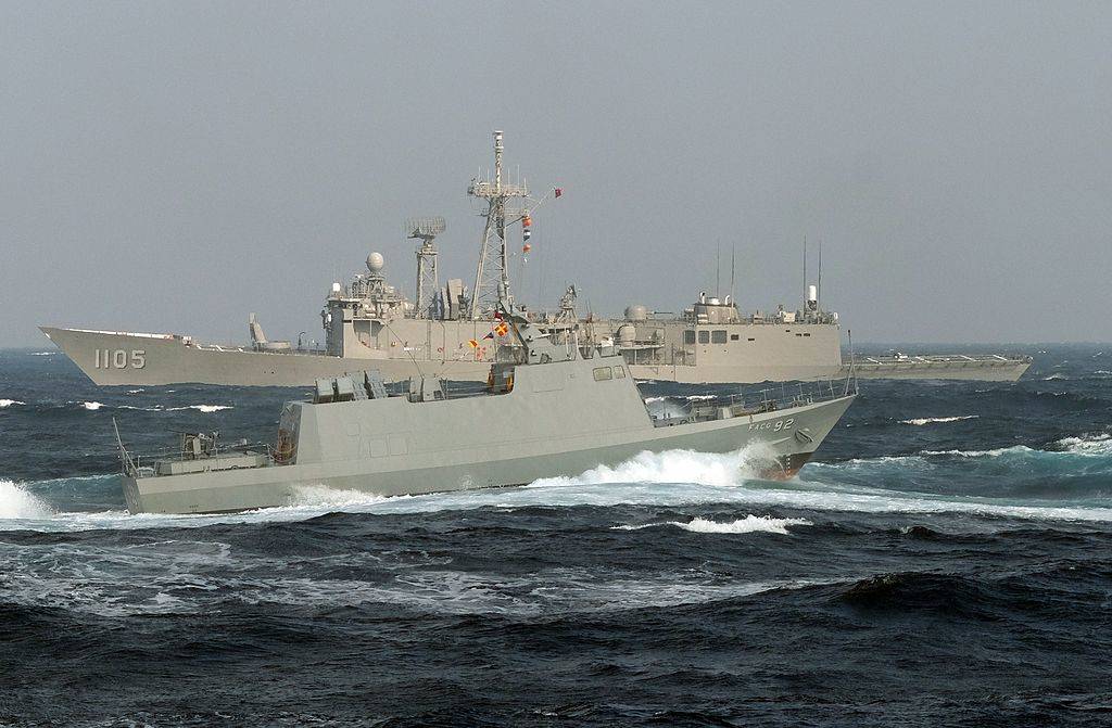 A locally made Kwong Hua six speed boat sails past a US-made frigate