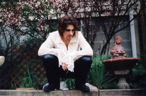 man sitting on sidewalk dressed like sexy vampire