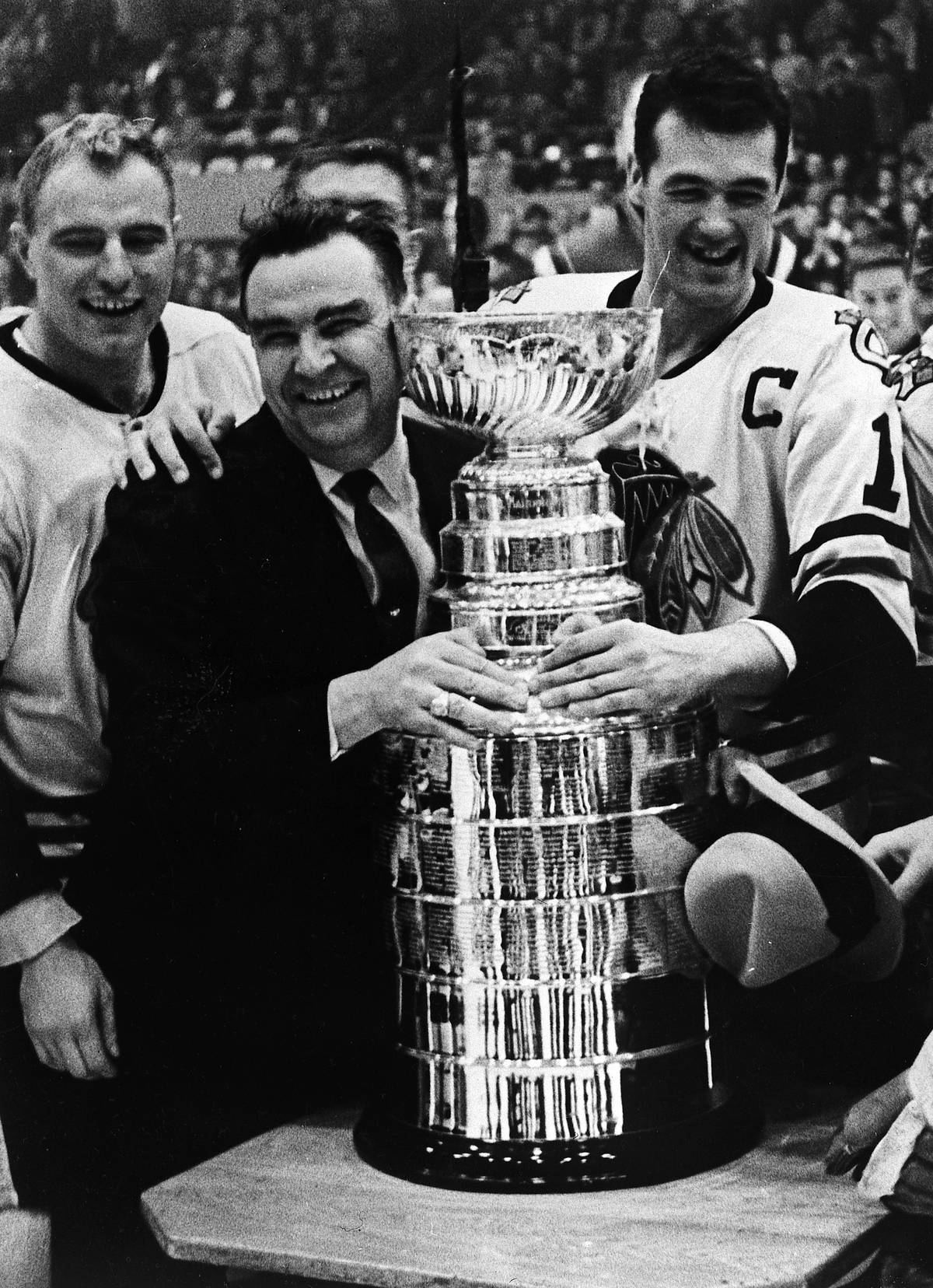 The Blackhawks coach and players embrace the Stanley Cup.