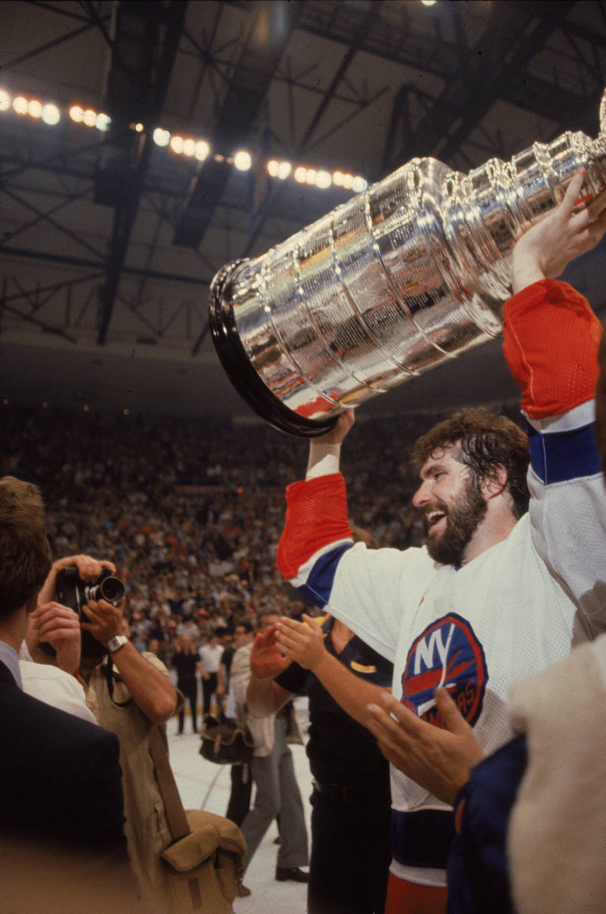 Clark Gillies of the New York Islanders holds the Stanley Cup over his head.