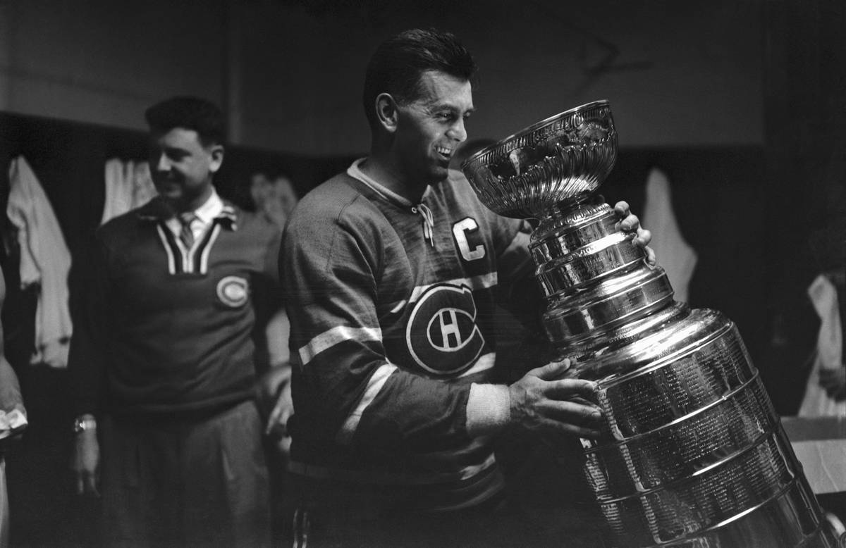 Maurice Richard tilts the Stanley Cup toward his mouth.