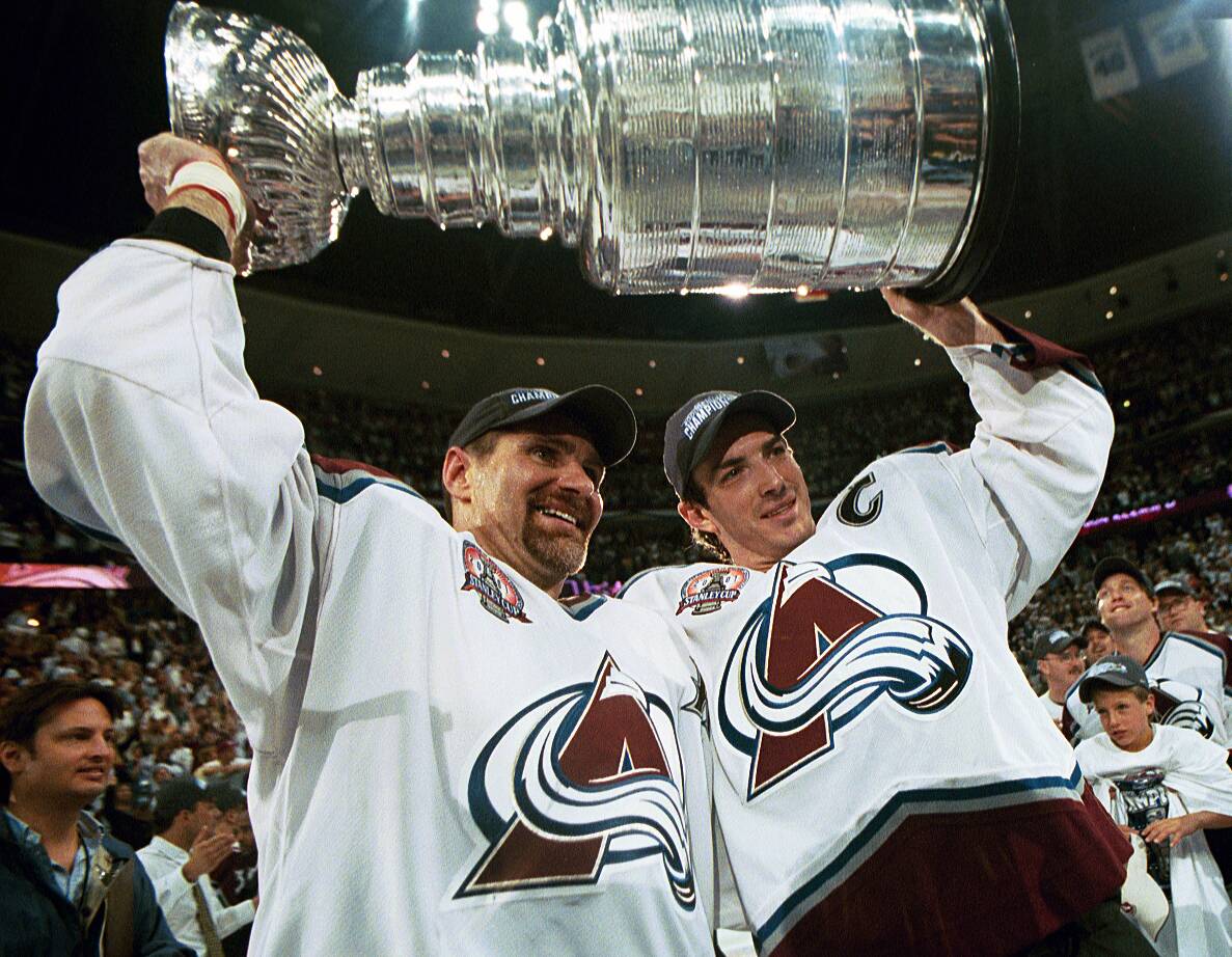 Ray Bourque and Joe Sakic hold the Stanley Cup over their heads.
