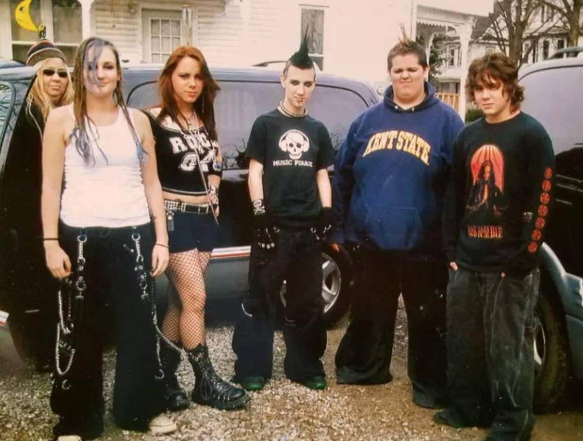 group of teens all in goth/emo clothing with a mom behind them