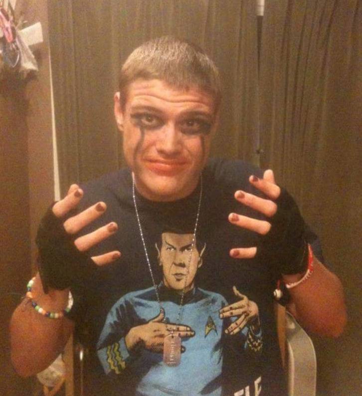 guy with eyes rimmed in black eyeliner, black fingerless gloves and nail polish
