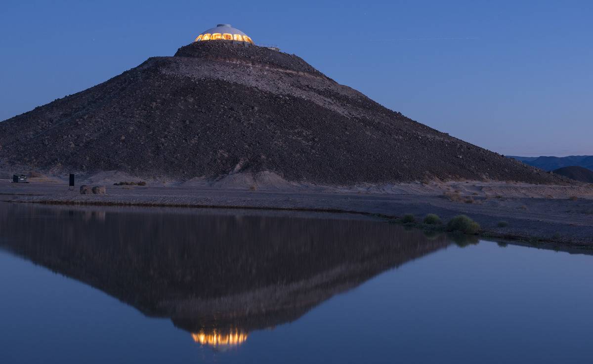 California's volcano house lights up at night on top of a hill.