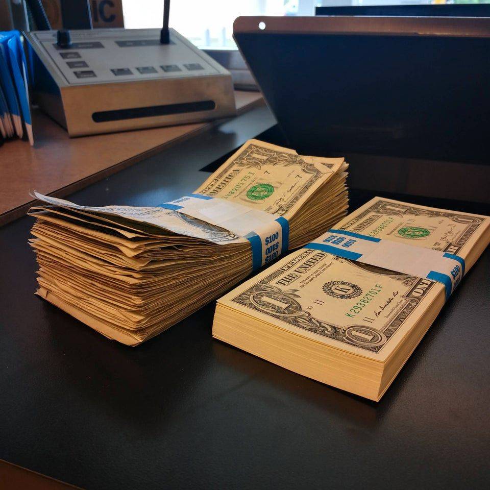 stack of new dollar bills next to old dollar bills