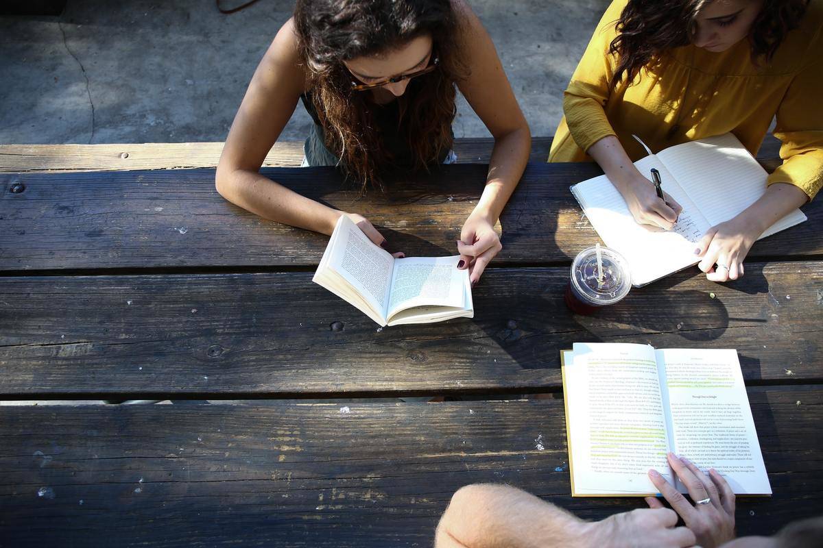 A group of people study at an outdoor table.