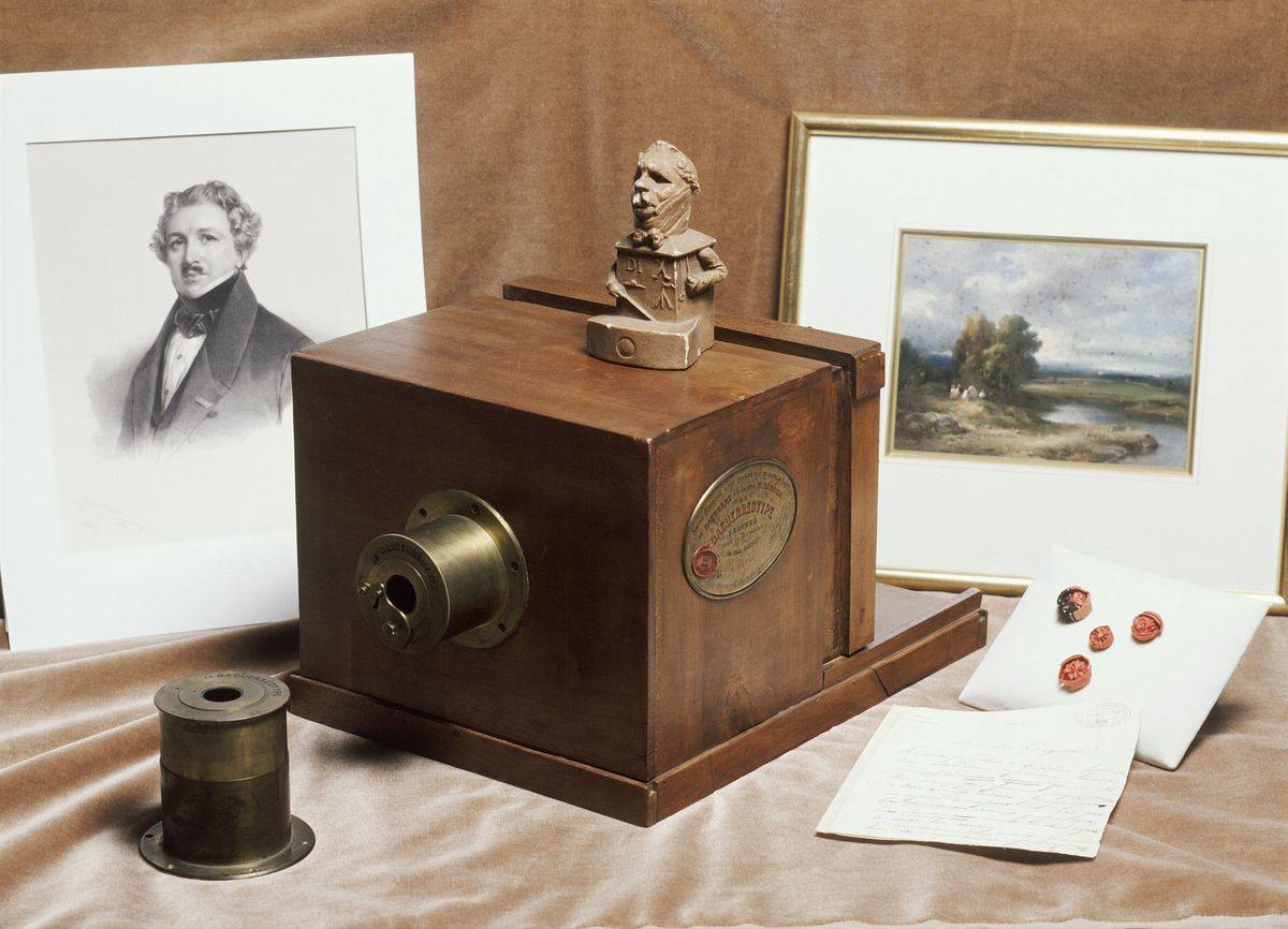 A Daguerreotype camera is in front of two pictures, 1839.
