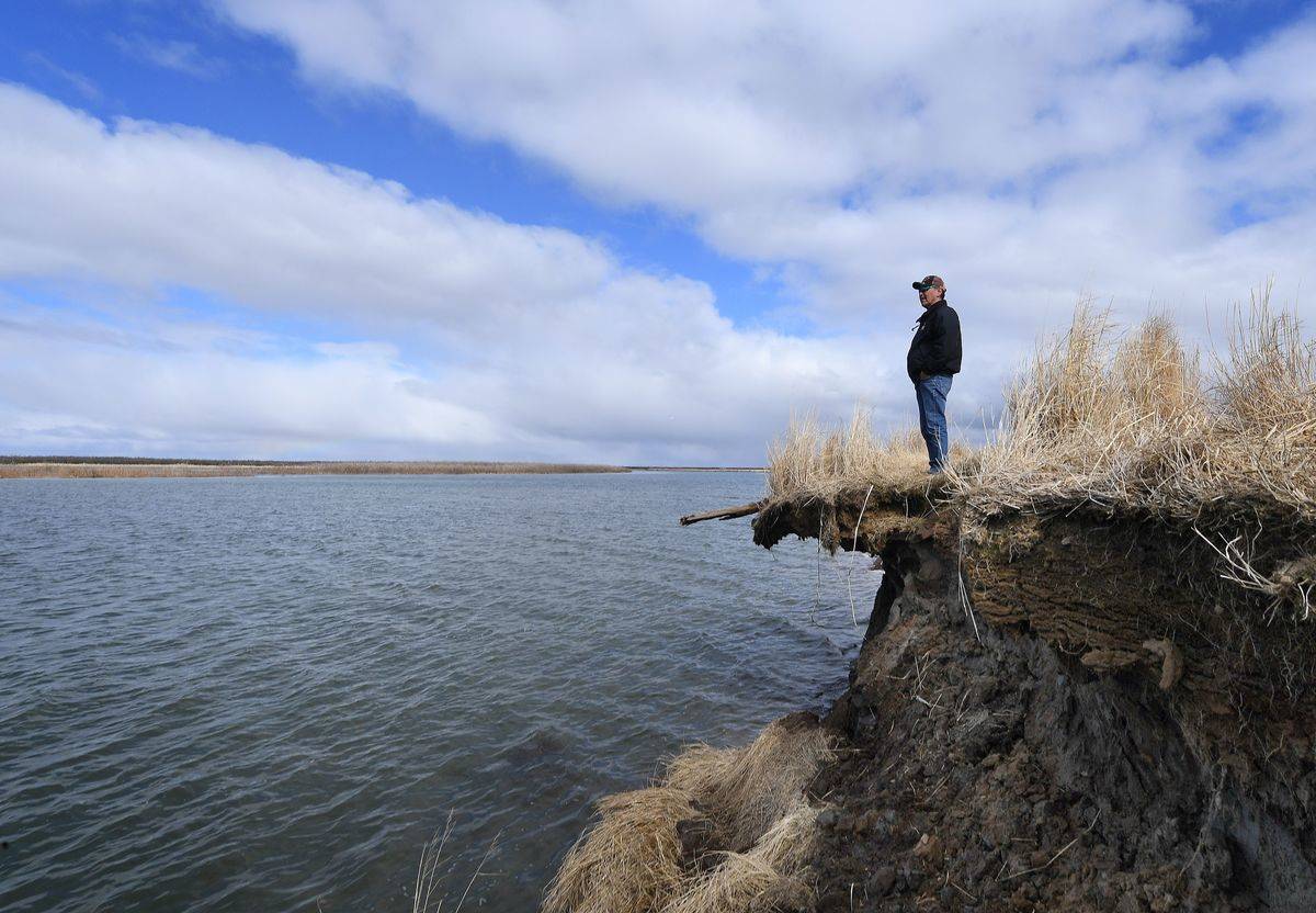 A scientist stands on a ledge that was eroded due to permafrost.