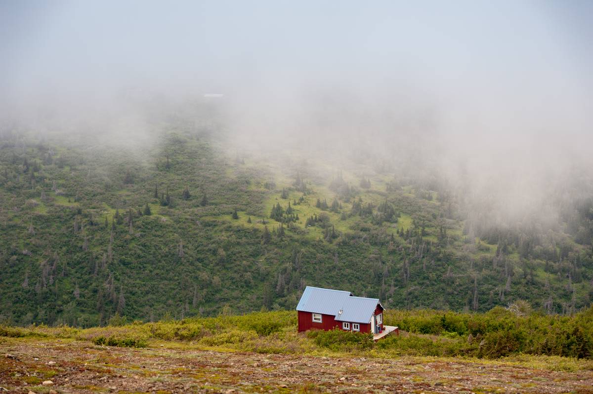 A red house is in the mountains of Chugach, AK.