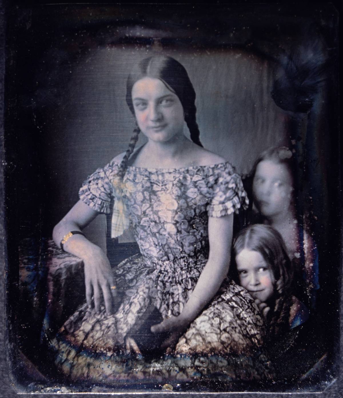 A young woman is photographed with two girls, 1850s.