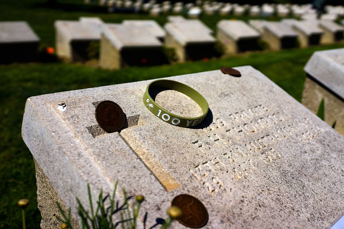 A few coins and a bracelet are on top of a grave.