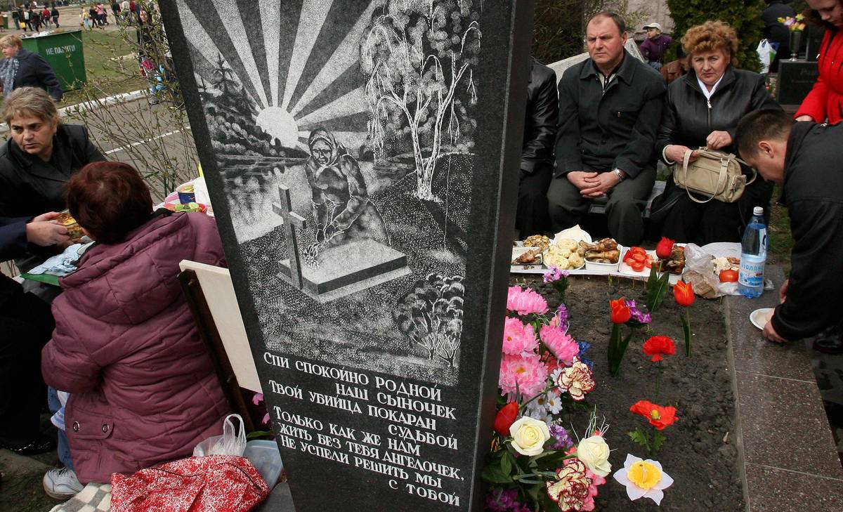 A family eats a meal by the grave of a loved one.