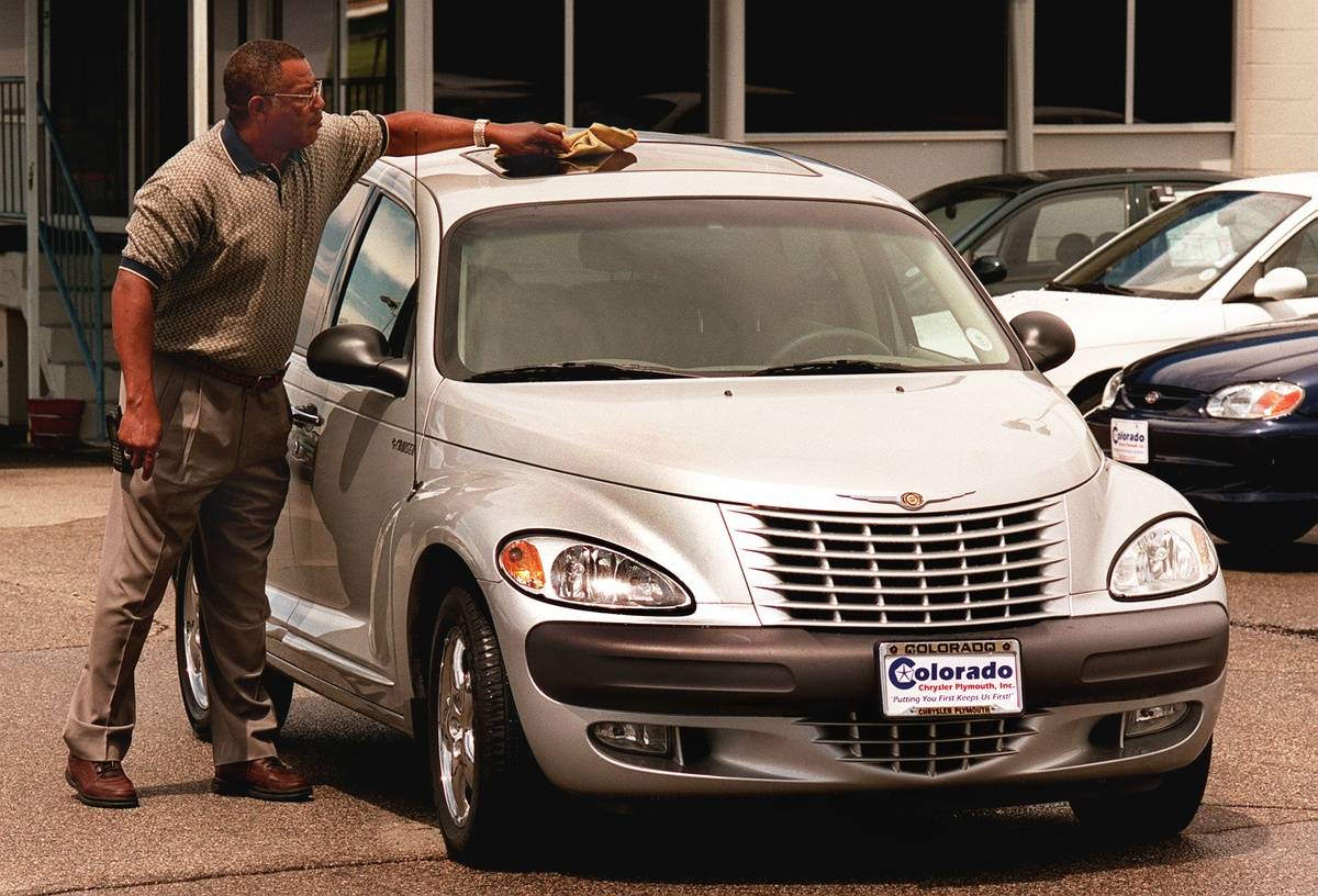 The new Chrysler PT Cruiser at Lithia Colo. Chrysler Plymouth dealership. Salesman Andy Dickerson wiping the rain drops from the roof.