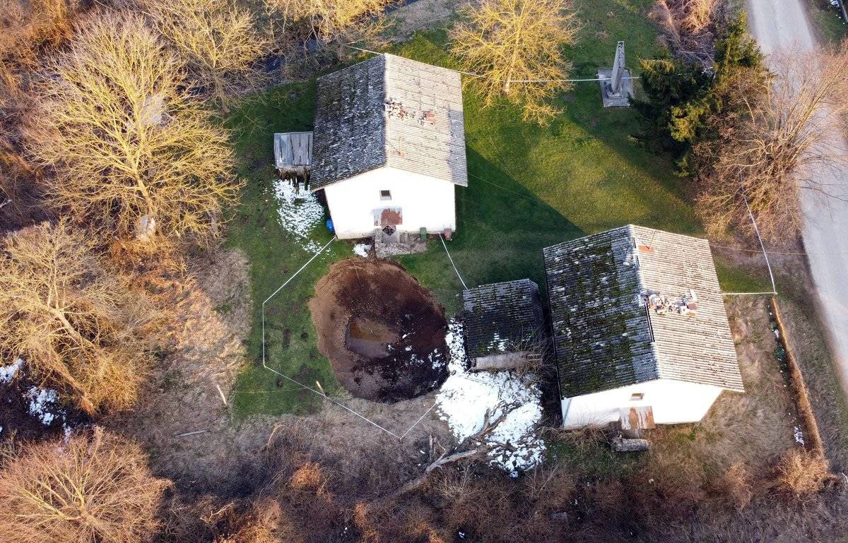 An aerial photo of a giant sinkhole in the village of Mecencani that appeared in a homeowners garden following an earthquake.
