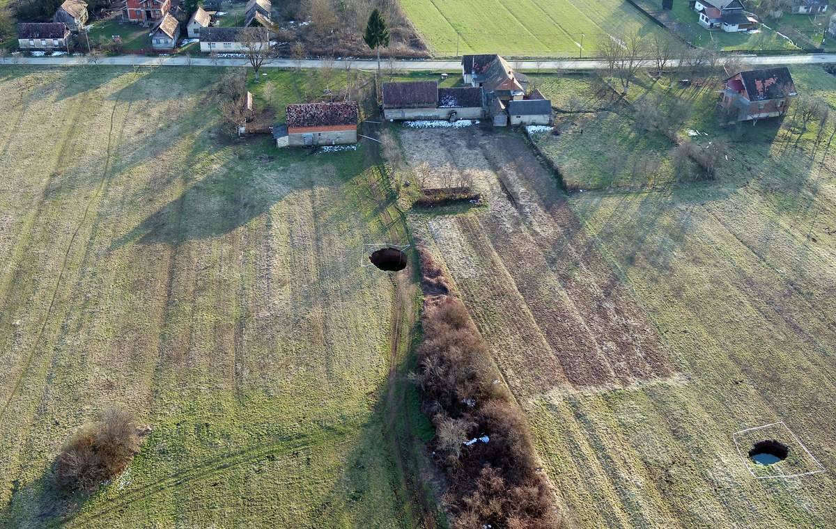 An aerial photo of two large sinkholes on someone's property in a Croatian village.