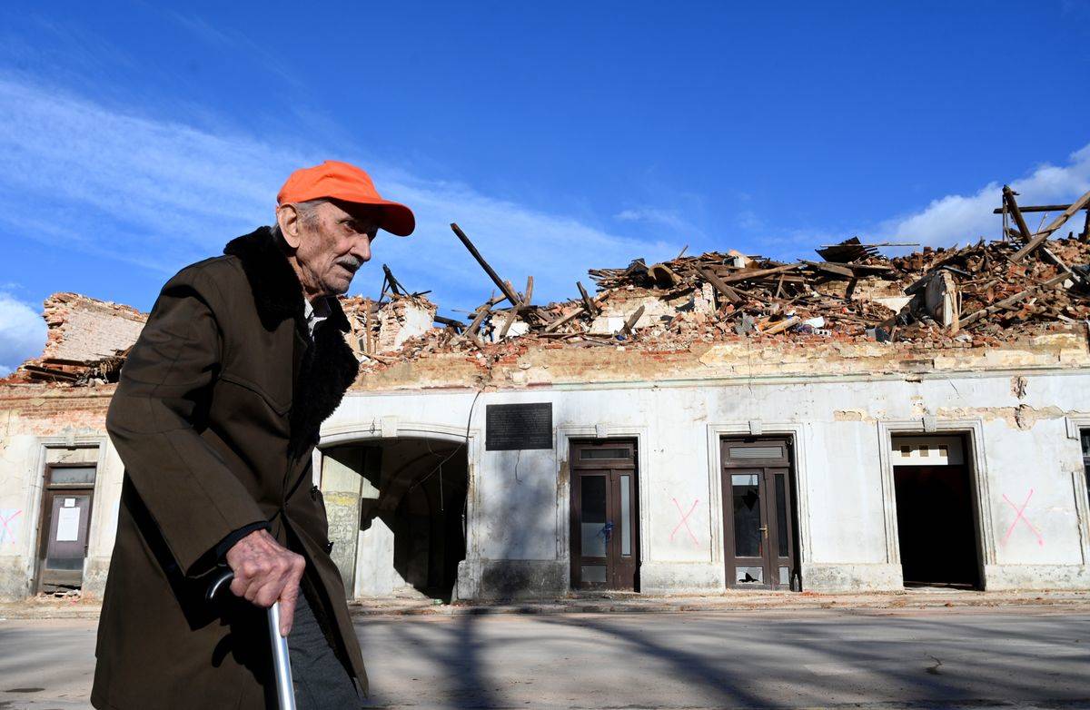A man walks past destroyed buildings in Petrinja on February 4, 2021. - More than a month ago, on December 29, 2020, the city of Petrinja was hit by a catastrophic earthquake measuring 6.4 on the Richter scale, forcing many people to leave their homes.