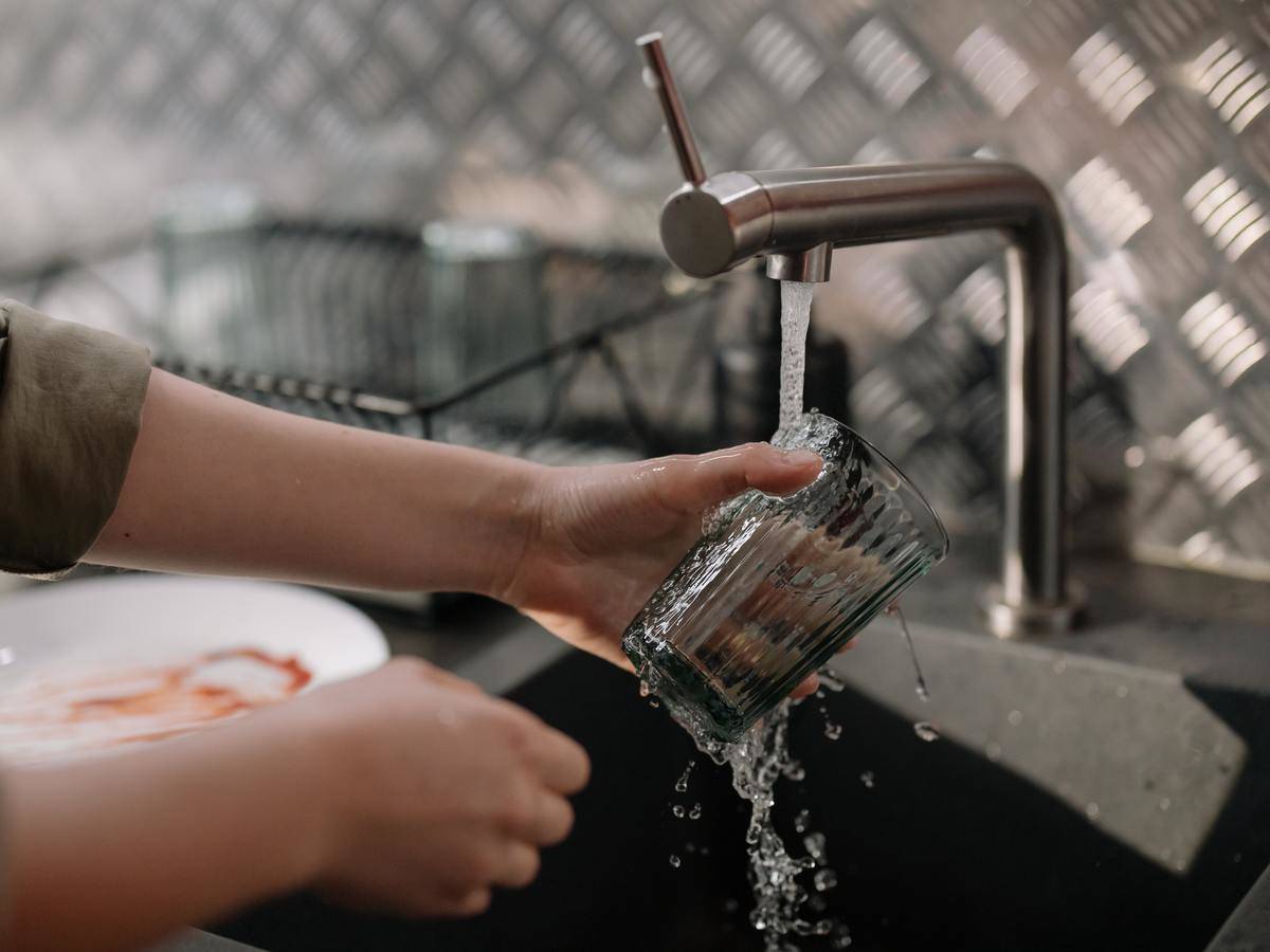 woman washing glass under tap