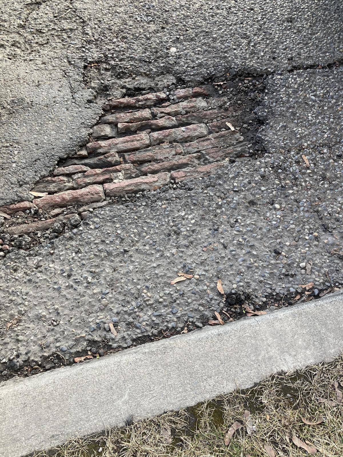 Cobblestone brick peeking out from beneath pavement