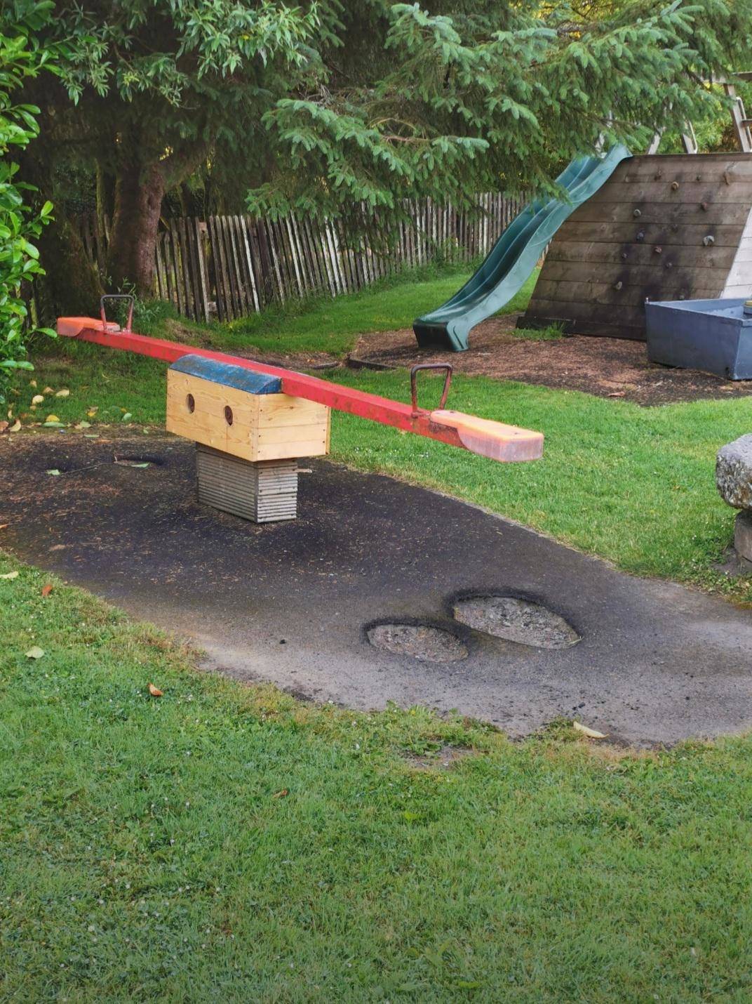 Worn-down asphalt under teeter-totter at playground