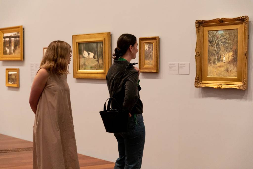 Attendees look at artwork at She-Oak and Sunlight: Australian Impressionism at The Ian Potter Centre: NGV Australia