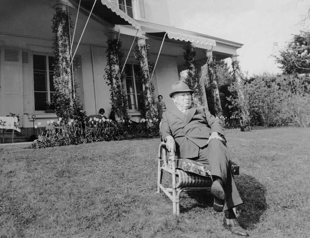 charlie chaplin sitting in a chair outside his house